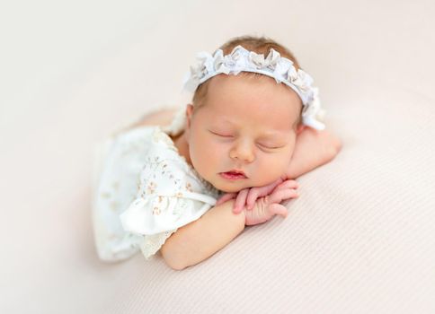 Nice newborn baby resting on stomach with head on hands