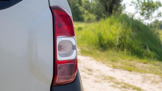 Right rear headlight. The rear of a small passenger hatchback or SUV of a white car with a group of taillights and a part of the trunk lid on the right. Red turn signal and brake light