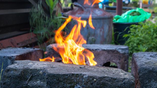 Fire blazes in a homemade barbecue grill in the backyard. Bonfire for cooking food on an open fire on wood. Camping. Camping concept