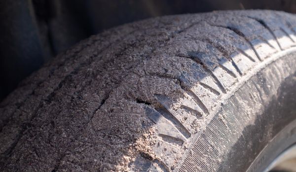 Dirty car wheel on a soil road to the countryside. Close-up detail of a tire. Transport, driving and car concept. The car got stuck in the sand