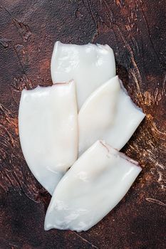 Raw Squid or Calamari tubes on a kitchen table. Dark background. Top view.