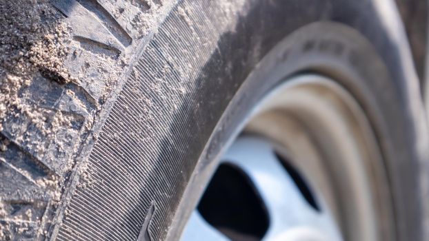 Dirty car wheel on a soil road to the countryside. Close-up detail of a tire. Transport, driving and car concept. The car got stuck in the sand