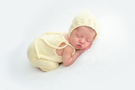 Lovely newborn in yellow suit resting on stomach