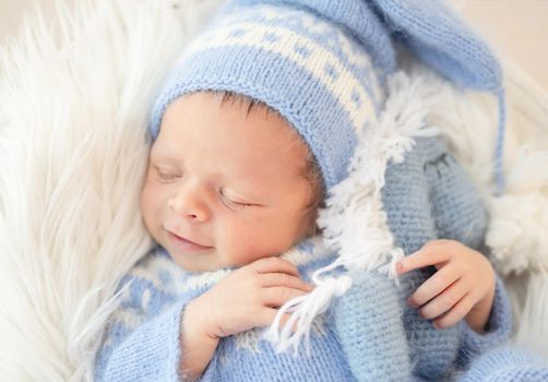 Smiling sleepy newborn holding knitted toy