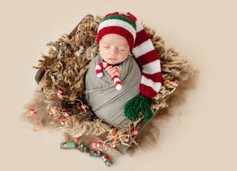 Funny newborn in christmas hat holding knitted candy