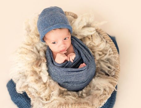 Charming newborn with open eyes lying in cradle