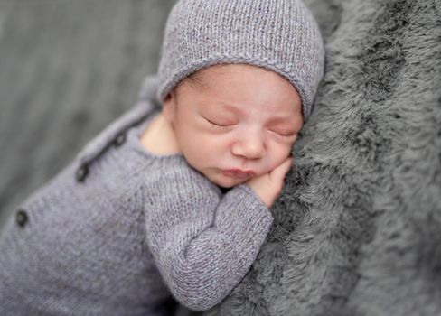 Sweet newborn in grey suit sleeping on stomach