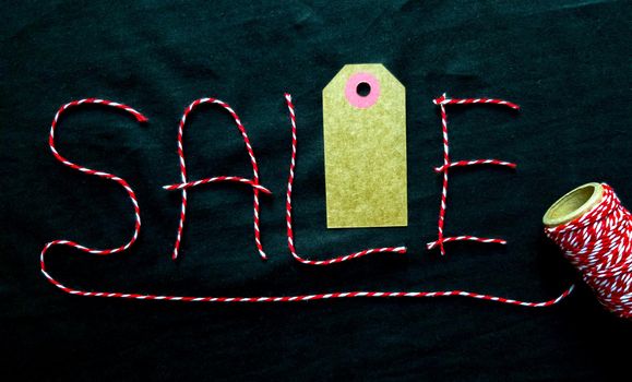 Sale, discount word made of red thread with a spool on a black background. Background, holiday concept. Black Friday - International Day of Shopping, Promotions, Discounts, Sales. Sales season is the fourth Thursday of November. Copy space, place for text, flat lay