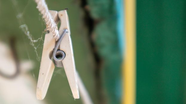 Plastic clothespins hang in a row on the rope. Rope outdoors, on a blurred background in a sunny garden. Clothesline on the street. Clothespins