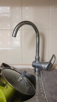 The kitchen utensils in the wash basin need to be washed. A pile of dirty dishes in the kitchen sink. Kitchen utensils need washing. Homework concept