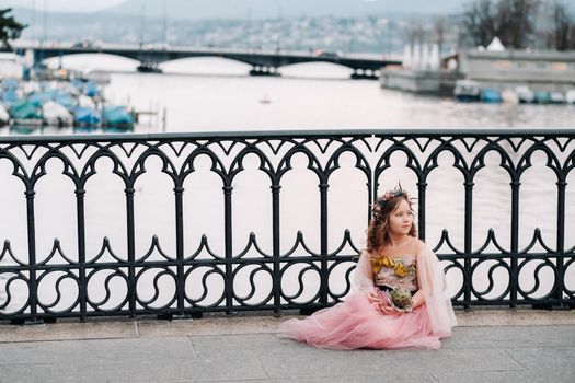 a little girl in a pink Princess dress with a bouquet in her hands walks through the old city of Zurich.Portrait of a girl in a pink dress on a city street in Switzerland.