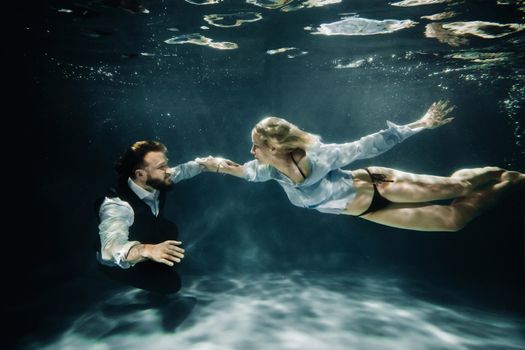 A woman and a man meet under water.A couple of lovers under water.