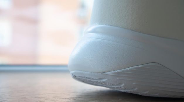 Low angle view of the outsole of the back of new white sneakers. Rubber sole on the heel of men's shoes. Sole for sports and walking shoes. Material texture of sports shoes