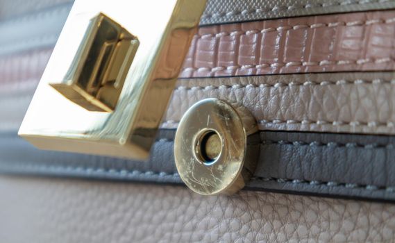 Close-up of a gold magnetic button-lock of an open elegant womens fashionable beige leather shoulder bag. Accessories, detail