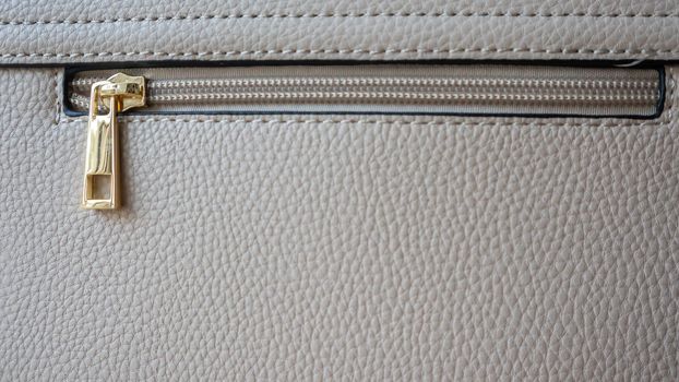 Natural or artificial leather texture. Fragment of a beige or powdery bag with a zipper and stitching. Zipper or clasp bag design element. Bovine skin texture with snake. Macro photo, selective focus