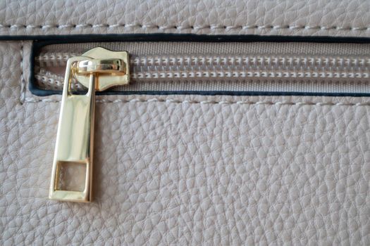 Natural or artificial leather texture. Fragment of a beige or powdery bag with a zipper and stitching. Zipper or clasp bag design element. Bovine skin texture with snake. Macro photo, selective focus