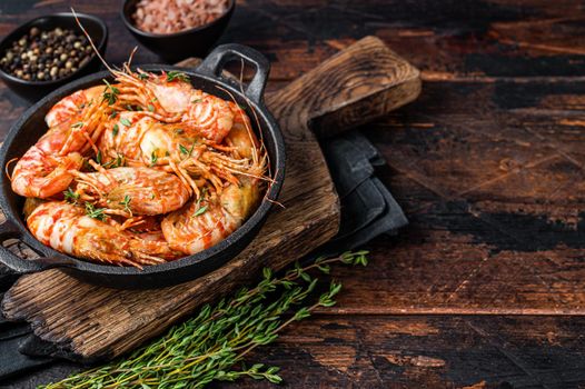 Cooking Greenland Shrimps Prawns in a pan with thyme and rosemary. Dark wooden background. Top view. Copy space.