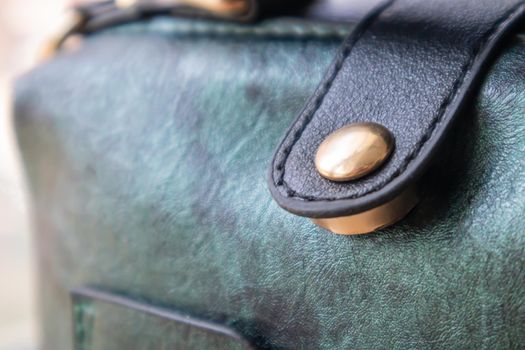 Close-up of gold magnetic button closure open elegant womens fashion green leather shoulder bag. Accessories, detail