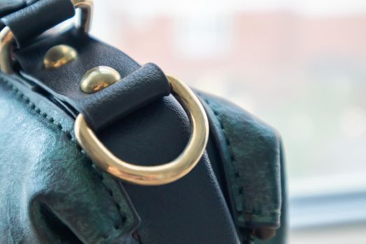 Metal gold loop oval ring attached to a leather bag. Selective focus. Part for a secure connection between two objects. Sewing accessories in the form of a ring for sewing bags, glossy