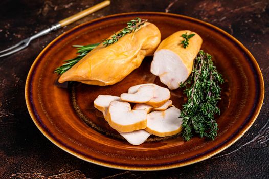 Hot Smoked chicken breast Poultry meat in a rustic plate with herbs. Dark background. Top view.