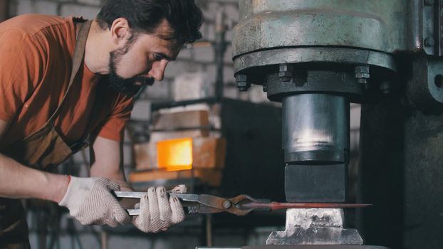 Molten metal is processed under pressure in the hands of a blacksmith, in the forge