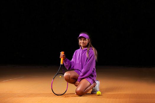 Beautiful girl tennis player with a racket on dark background wiht lights