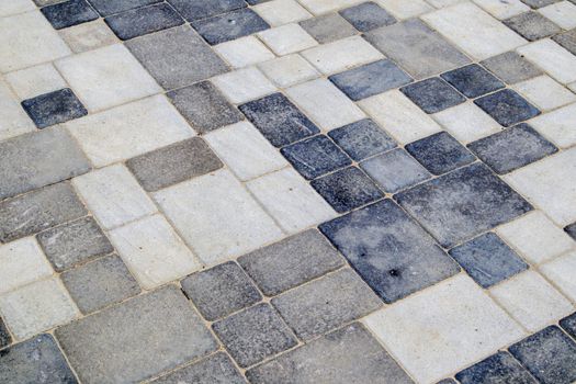 Concrete or paved newly laid gray paving slabs or stones for floors or walkways. Concrete paving slabs in the backyard or road paving. Garden brick path in the courtyard on a sandy foundation