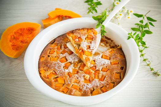 sweet pumpkin pie with pumpkin slices in a ceramic mold on a wooden table