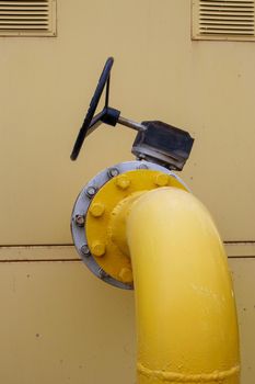Yellow gas pipe with a tap. Oil pipeline fittings in the oil and gas industry. Oil and gas processing plant with pipeline fittings. Industrial safety valve