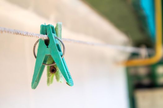 Plastic clothespins hang in a row on the rope. Rope outdoors, on a blurred background in a sunny garden. Clothesline on the street. Clothespins
