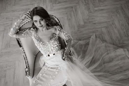 A luxurious bride in a wedding dress in the morning in her interior.Black and white photo.