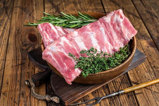 Raw pork spare ribs in wooden plate witn meat fork. wooden background. Top view.