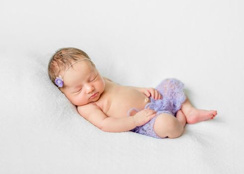 lovely sleeping newborn girl with hands under head in violet knitted panties