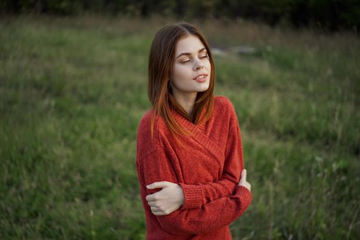 woman in a red sweater outdoors in the field nature rest. High quality photo