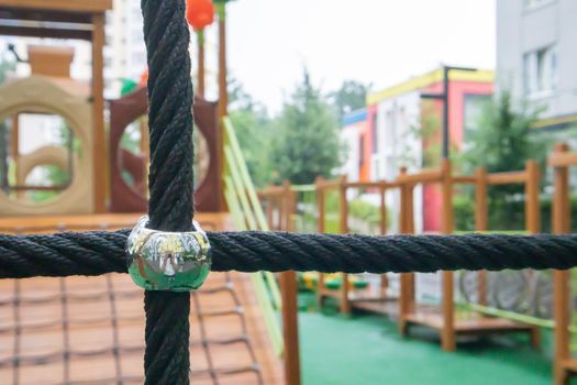 A courtyard of high-rise buildings with a modern and large playground made of wood and plastic on a rainy summer day without people. Empty outdoor playground. A place for children's games and sports