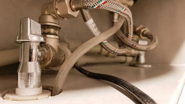 Connection of water supply, hot and cold water to the boiler. Hose for hot and cold water in the bathroom. Plumbing connections for a domestic electric water heater