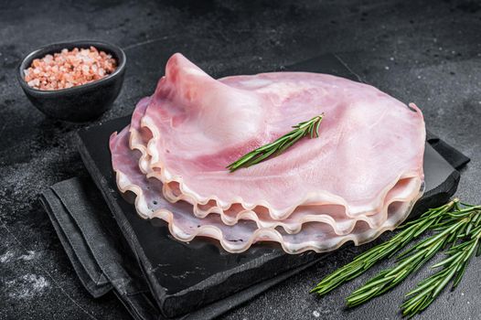 Sliced pork ham on marble board. Black background. Top view.