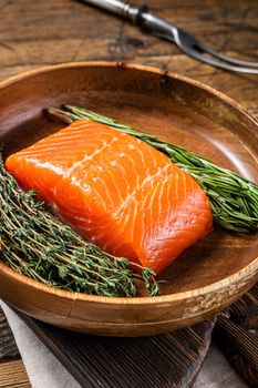 Healthy food - fresh salmon fillet steak with herbs. Wooden background. Top view.