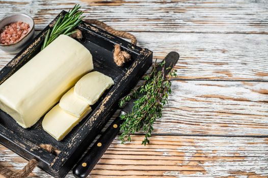 Butter Margarine block in a wooden tray with herbs. White wooden background. Top view. Copy space.