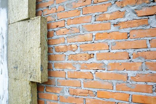 Thermal insulation of the facade of a brick building from the outside. Thermal insulation of brickwork with mineral wool. Thermal insulation of a house wall at a construction site