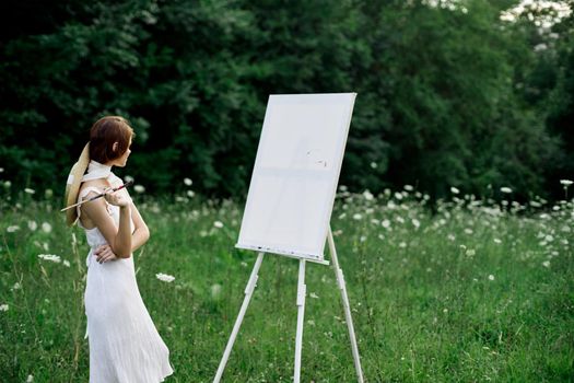 Woman in white dress paints a picture outdoors hobby creative. High quality photo