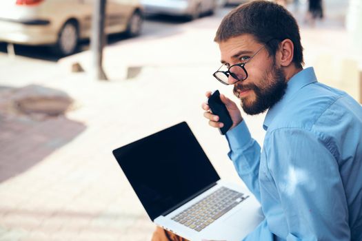 a man in a blue shirt on the street with a laptop manager. High quality photo