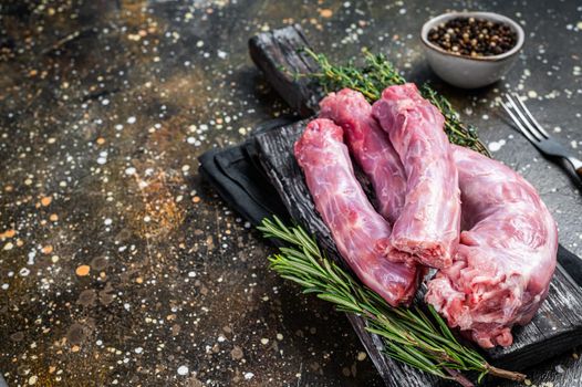 Raw Turkey or chicken necks meat on a wooden board with thyme. Brown background. Top View. Copy space.