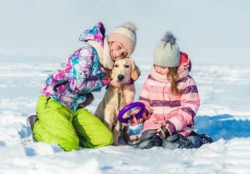 Cheerful girls with cute dog on winter walk