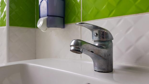 Old aluminum sink mixer. Water tap in the toilet for clean hands