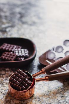 Assortment of different chocolate types in wooden carved plate, with vintage props on the background