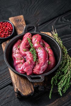 Raw mutton tenderloin Fillet Meat, lamb sirloin in rustic pan with thyme. Black wooden background. Top view.