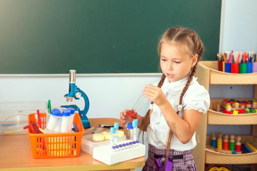 Young girl making science chemistry experiments in school laboratory. Education concept.