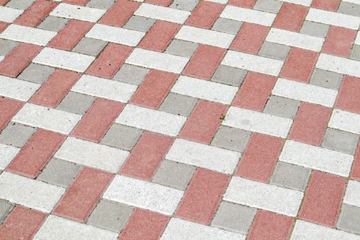 Concrete or paved newly laid gray and red paving slabs or stones for floors or walkways. Concrete paving slabs in the backyard or road paving. Garden brick path in the courtyard on a sandy foundation