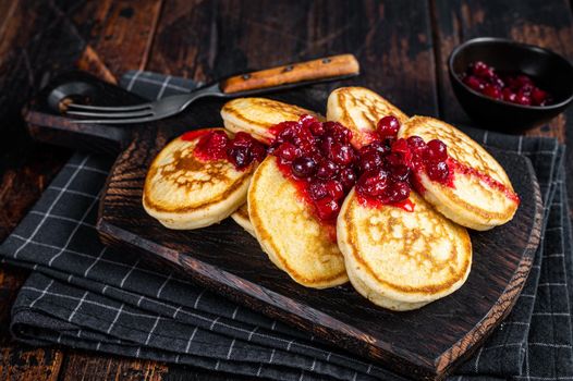 Stack of cranberry syrup pancakes on wooden board. Dark wooden background. Top View.